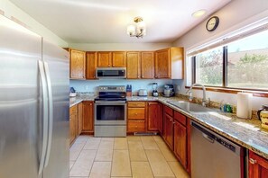 A kitchen with wooden cabinets, stainless steel appliances, a granite countertop, and a window with a view. - Two-story, dog-friendly townhouse with a washer/dryer & a full kitchen (Pagosa Springs)