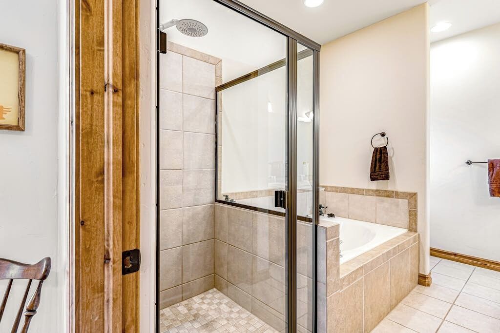 A modern bathroom with a glass-enclosed shower, a bathtub, and a toilet.