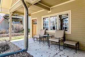 Eine überdachte Terrasse mit Gartenmöbeln, einer Tür und Fenstern.