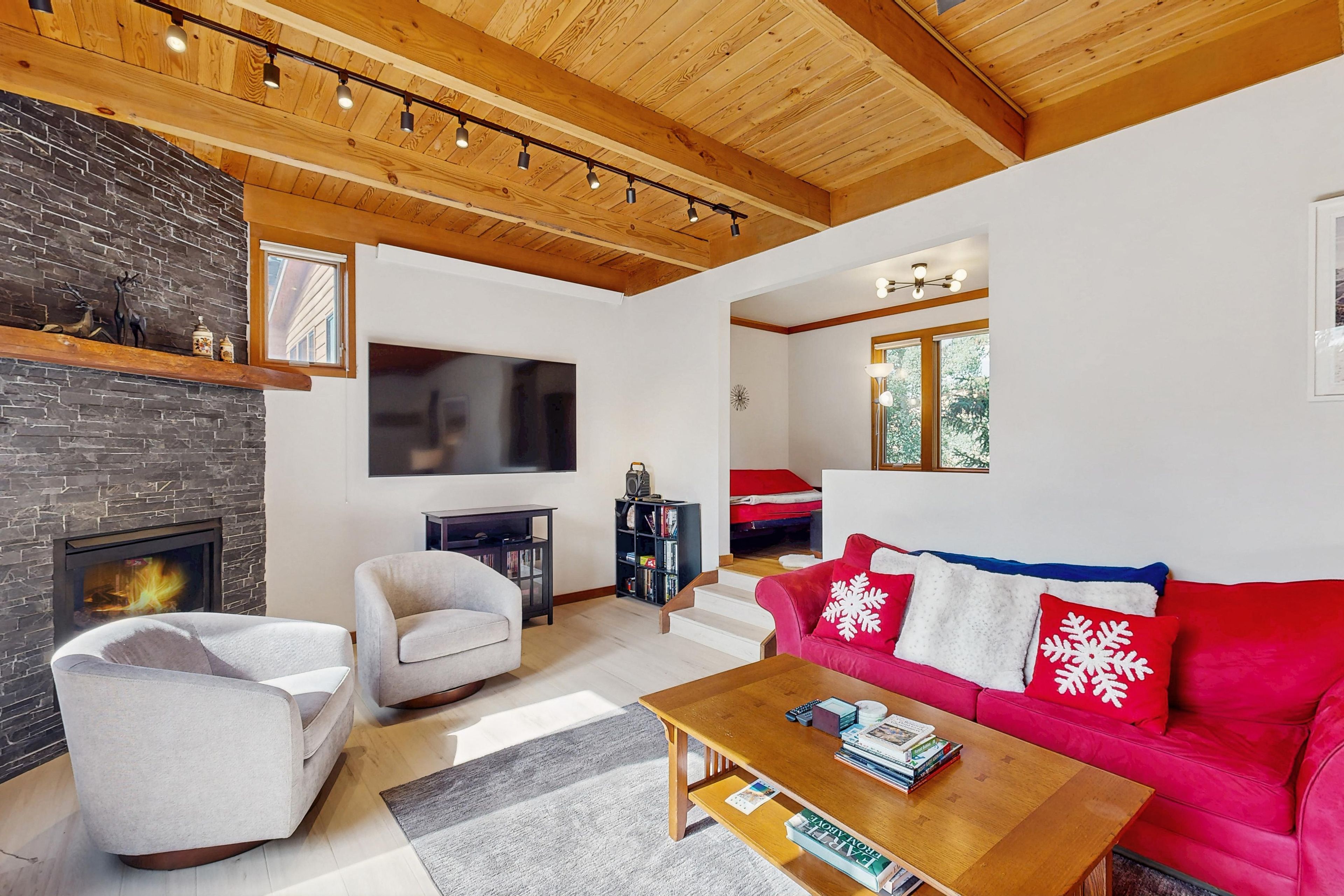 A living room with a fireplace, a television, a red sofa, and a wooden coffee table.