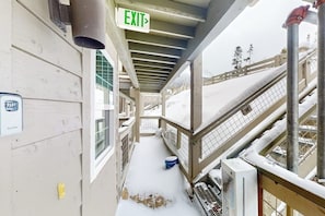 A covered outdoor area with an exit sign, a snow-covered ground, and a metal railing. - Dog-Friendly Home with Trail Access, Gorgeous Views (Silverthorne)