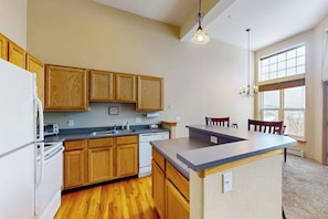 A kitchen with wooden cabinets, a central island, a dishwasher, and a window providing natural light. - Dog-Friendly Home with Trail Access, Gorgeous Views (Silverthorne)