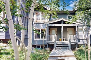 Ein zweistöckiges Haus mit Veranda, einem kleinen Tisch und einer Bank.
