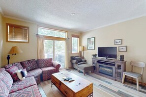 Ein Wohnzimmer mit Sofa, Hocker, Couchtisch, Fernseher und Unterhaltungseinrichtung.
