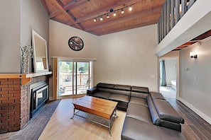 Ein Wohnzimmer mit Kamin, einer Couch, einem Couchtisch aus Holz und einer Wanduhr.