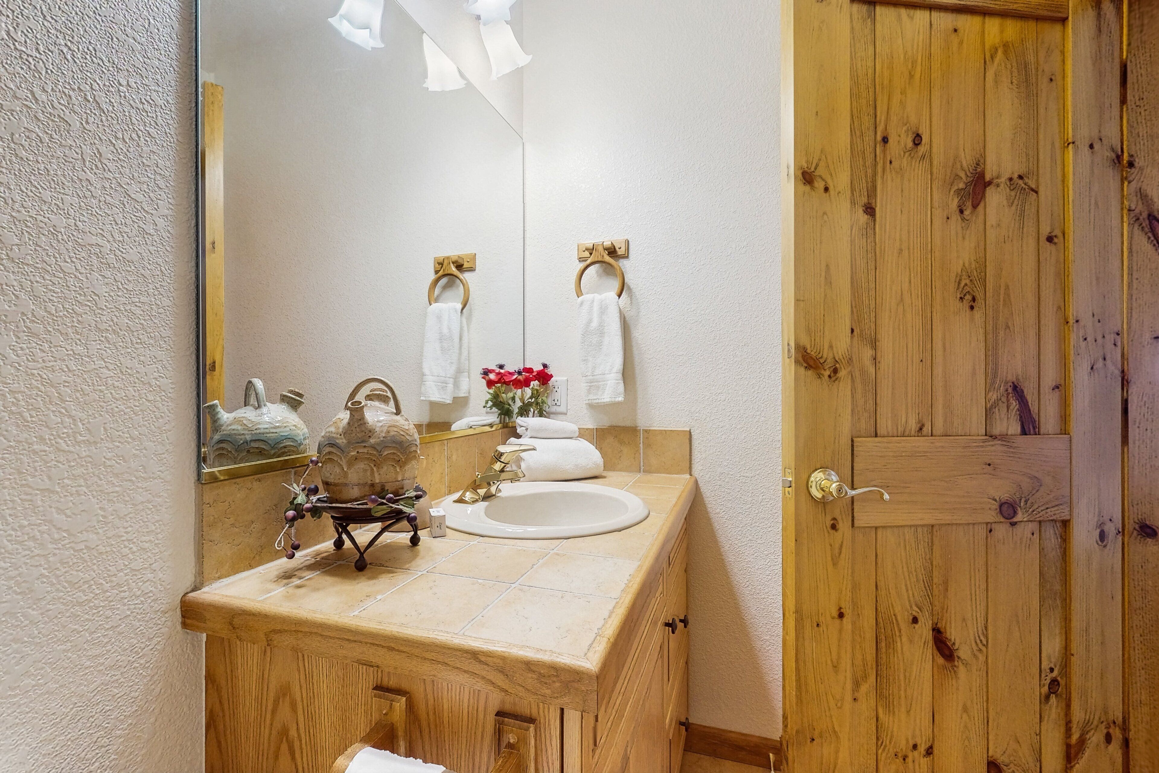 A wooden vanity with a sink, a mirror, and a towel rack.