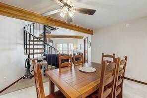 A dining area with a wooden table and chairs, a ceiling fan, and a spiral staircase. - Spacious condo with shared pool & hot tub - great location (Silverthorne)