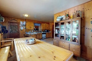 Eine Holzküche mit einer zentralen Kochinsel, Holzsäcken und einer Vitrine mit Glastüren.