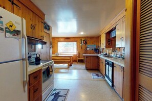 Eine kleine Küche mit Holzschränken, einem Kühlschrank, einem Herd und einem Spülbecken.