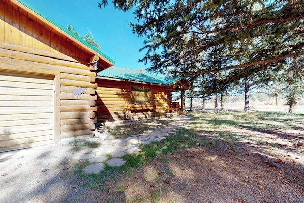 Eine Blockhütte mit Veranda, einem überdachten Sitzbereich im Freien und einem Kiesweg zum Eingang.