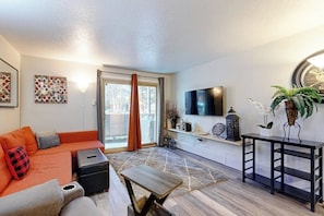 A modern living room with a sofa, a coffee table, a TV, and decorative items. - Cozy condo in great location - access to shared pool & game room (Dillon)