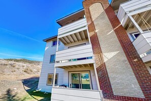 A multi-story residential building with a brick chimney, balconies, and a clear sky. - Cozy condo in great location - access to shared pool & game room (Dillon)