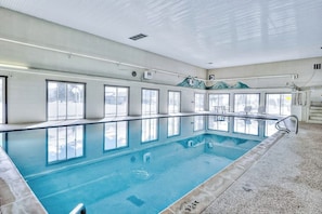 An indoor swimming pool with clear windows, a tiled floor, and a metal railing. - Cozy condo in great location - access to shared pool & game room (Dillon)