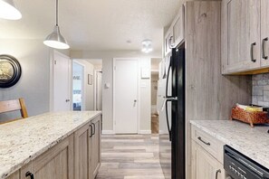 A kitchen with a granite countertop, wooden cabinets, a black refrigerator, and a hanging pendant light. - Cozy condo in great location - access to shared pool & game room (Dillon)