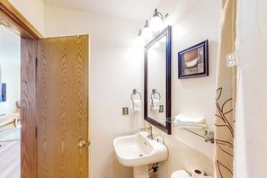 A bathroom with a wooden door, a white sink, a mirror, and a towel rack. - Wildernest condo with indoor pool and sauna, 10 miles to Keystone (Silverthorne)