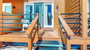 En träveranda med en glasdörr som ingång, en skylt med numret ”504B” och en stol utanför.