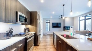 A modern kitchen with dark wood cabinets, stainless steel appliances, and a central island with a sink. - Modern riverfront condo w/ a gas fireplace, washer/dryer & private patio (Silverthorne)