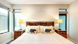 A bedroom with a large bed, two bedside tables, and a wooden headboard. - Modern riverfront condo w/ a gas fireplace, washer/dryer & private patio (Silverthorne)