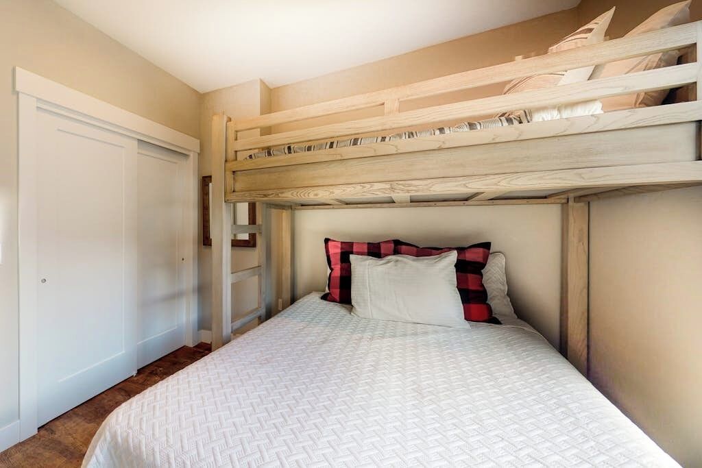Un lit superposé avec une tête de lit blanche et un lit inférieur recouvert d’une courtepointe blanche matelassée.