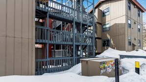 Un edificio de varios pisos con una escalera metálica y el suelo cubierto de nieve.