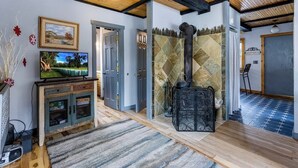 Una habitación con televisión, chimenea y puerta que da a otra habitación.