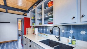 Una cocina con encimera blanca, pileta negra y salpicadero con diseño azul y blanco.