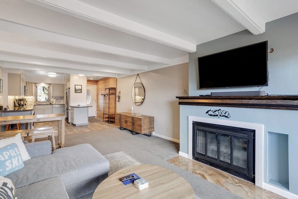 A modern living room with a fireplace, a flat-screen TV, a sofa, and a dining area.
