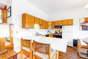 Eine moderne Küche mit Holzschränken, einer weißen Arbeitsplatte und einem Essbereich mit Holzkästen.