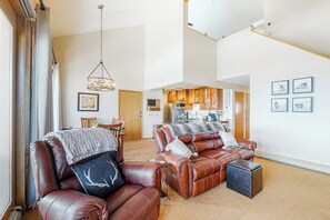 Ein geräumiges Wohnzimmer mit Ledersofas, einem Essbereich und einer Küche im Hintergrund.