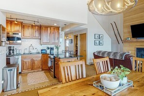 Eine moderne Küche mit Holzschränken, Edelstahlgeräten und einem Essbereich mit einem Holztisch und Stühlen.