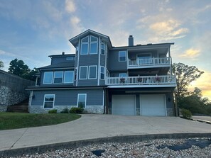 A two-story house with a garage, a balcony, and a stone wall. - Beaver lakeview home with indoor pool.Boat launch and swim area in neighborhood. (Rogers)