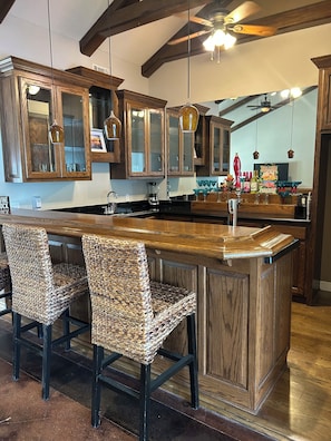 A kitchen with wooden cabinets, a central island with bar stools, and hanging pendant lights. - Beaver lakeview home with indoor pool.Boat launch and swim area in neighborhood. (Rogers)