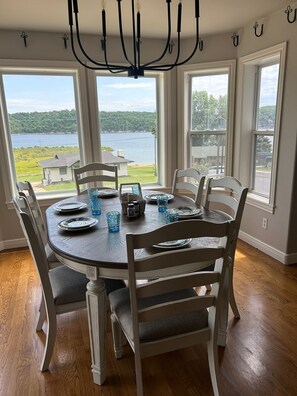 A dining room with a round table, six chairs, and a chandelier. - Beaver lakeview home with indoor pool.Boat launch and swim area in neighborhood. (Rogers)