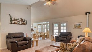 A living room with leather sofas, a wooden coffee table, and a dining area with a table and chairs. - Hilltop Home w/ Great Mountain Views, Back Porch, WiFi, W/D & Attached Garage (South Fork)