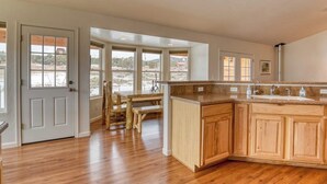 A kitchen with wooden cabinets, a granite countertop, and large windows. - Hilltop Home w/ Great Mountain Views, Back Porch, WiFi, W/D & Attached Garage (South Fork)
