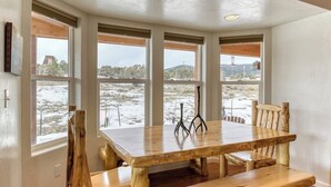 A dining area with a wooden table and chairs, large windows with a view of a snowy landscape, and a ceiling with recessed lighting. - Hilltop Home w/ Great Mountain Views, Back Porch, WiFi, W/D & Attached Garage (South Fork)