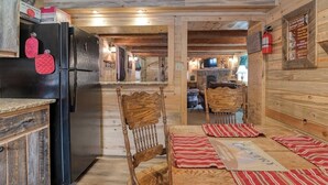 A wooden interior with a kitchen area, a dining table with striped placemats, and a wooden chair. - Remodeled Cabin In South Fork w/Free WiFi/Furnished Patio/Private Washer/Dryer (South Fork)