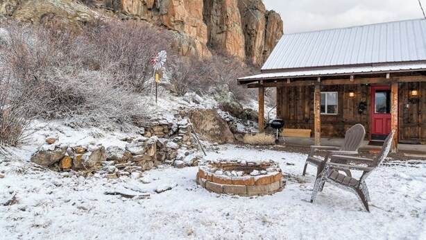 A rustic cabin with a stone fire pit, wooden benches, and a red door. - Remodeled Cabin In South Fork w/Free WiFi/Furnished Patio/Private Washer/Dryer (South Fork)