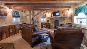 A cozy log cabin interior with a fireplace, leather furniture, and a television. - Remodeled Cabin In South Fork w/Free WiFi/Furnished Patio/Private Washer/Dryer (South Fork)