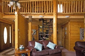 Ein Holzinnenraum mit einem Ledersofa, einer Treppe und einem Essbereich.