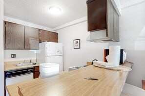 Eine Küche mit Holzausstattung, einem weißen Kühlschrank, einem Geschirrspüler und einer Holz Arbeitsplatte.