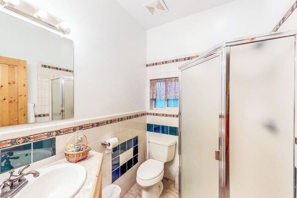 A bathroom with a sink, toilet, and shower area. - Lovely cabin on pond with balcony, outdoor fire, and private hot tub (South Fork)