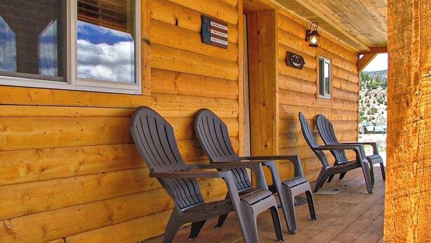 A wooden cabin with a porch, Adirondack chairs, and a sign. - Remodeled, Mountain View Cabin w/ Fireplace, Firepit & WiFi - Dogs Welcome (South Fork)