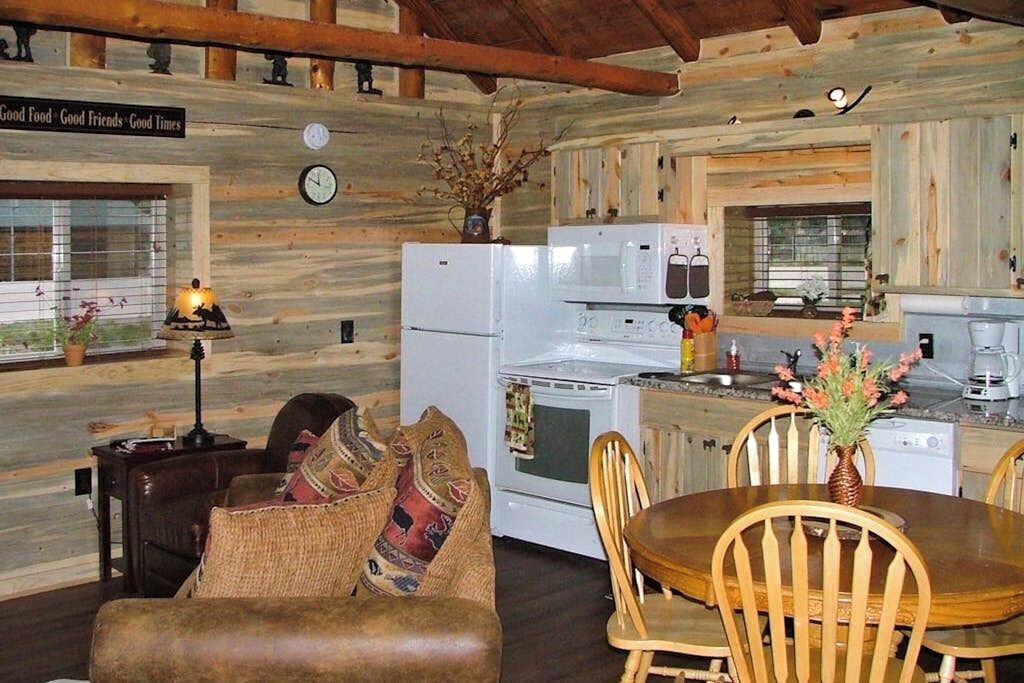 A log cabin interior with a dining area, kitchen, and a cozy living space.