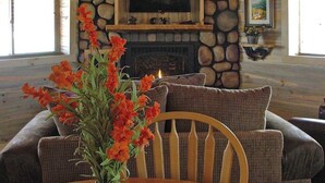 A cozy room with a stone fireplace, a television mounted above it, and a window with curtains. - Remodeled, Mountain View Cabin w/ Fireplace, Firepit & WiFi - Dogs Welcome (South Fork)