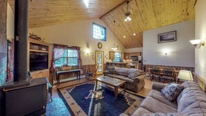 Ein gemütliches Wohnzimmer mit Kamin, einer Couch, einem Couchtisch und einem Essbereich mit Tisch und Stühlen.