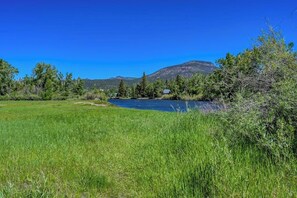 Un río con una casa en la orilla, rodeada de vegetación y montañas.