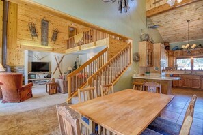 Ein großzügiger Wohnbereich mit einer Holztreppe, einem Kamin und einer Küche mit Holzausstattung.