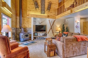 Ein gemütliches Blockhaus-Interieur mit Kamin aus Stein, einem Fernseher und einer komfortablen Sitzecke.