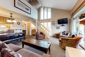 Ein geräumiges Wohnzimmer mit Treppe, Fernseher und Essbereich.